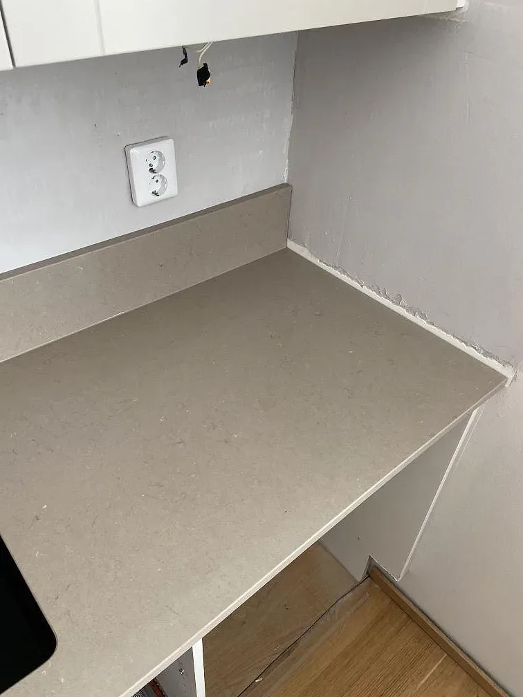 Greige Silestone Coral Clay köksbänkskiva med uppvikt stenkant mot gipsväggen i ett kök under inredning i Lomma.