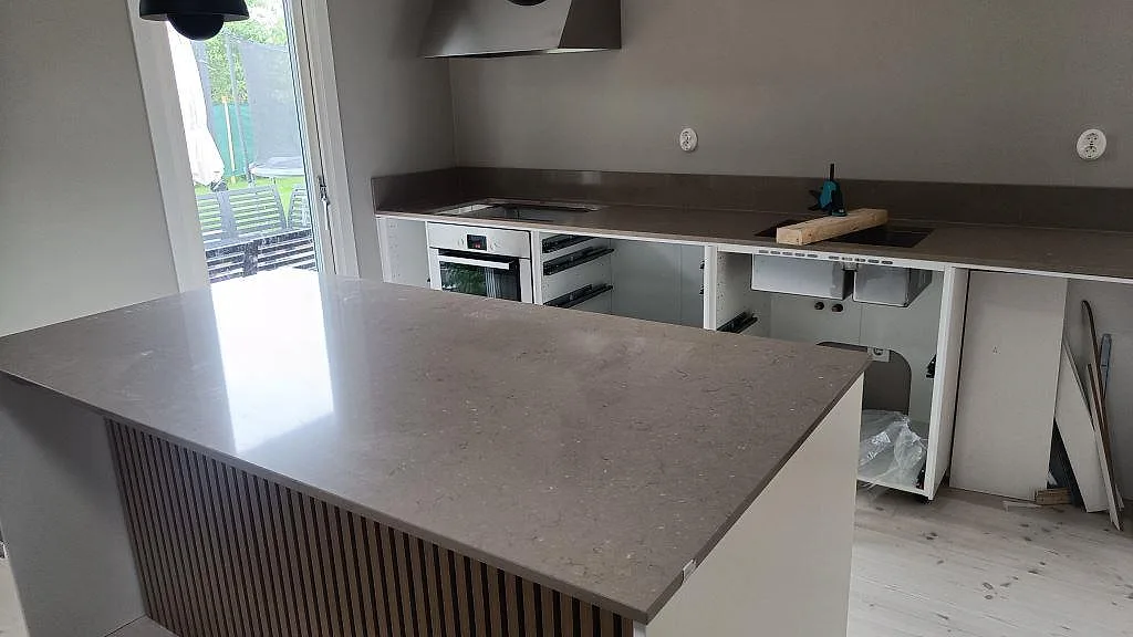 Polerad köksbänkskiva i Silestone Coral Clay med köksö, raka väggbänkar och underlimmad dubbel diskho i ett kök i Lomma.