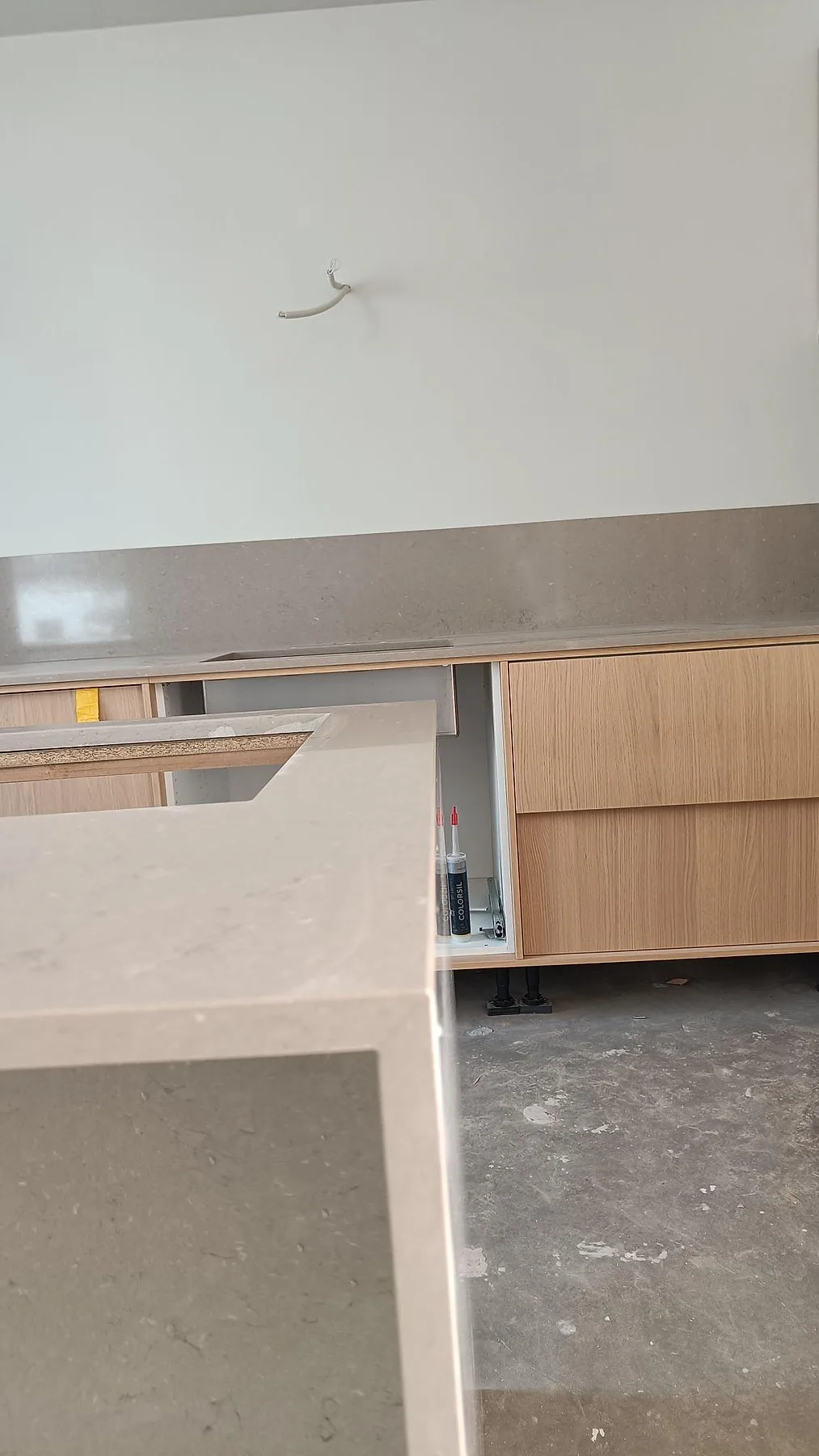 Vertikal vy av polerad Silestone Coral Clay i kvartskomposit med köksödel, bakre bänkskiva och uppvikt stänkskydd i ett kök i Lomma.