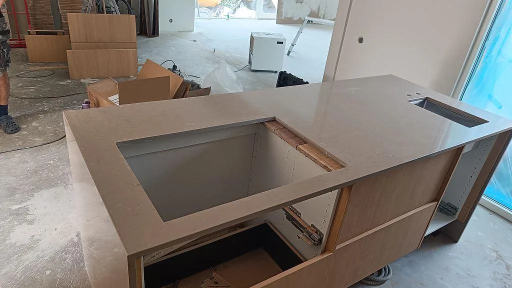 Ovanifrån syns en polerad Silestone Coral Clay bänkskiva i kvartskomposit med stor öppning i köksön och diskhozon vid fönstret i Lomma.
