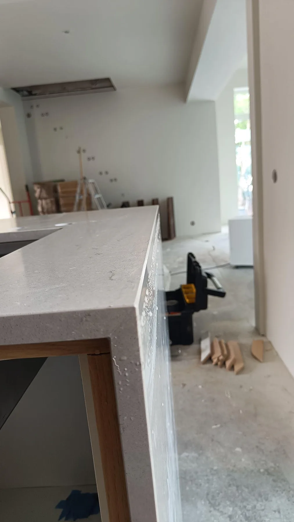 Kantdetalj av polerad Silestone Coral Clay bänkskiva i kvartskomposit med lodrät stenfront och pågående köksmontering i Lomma.