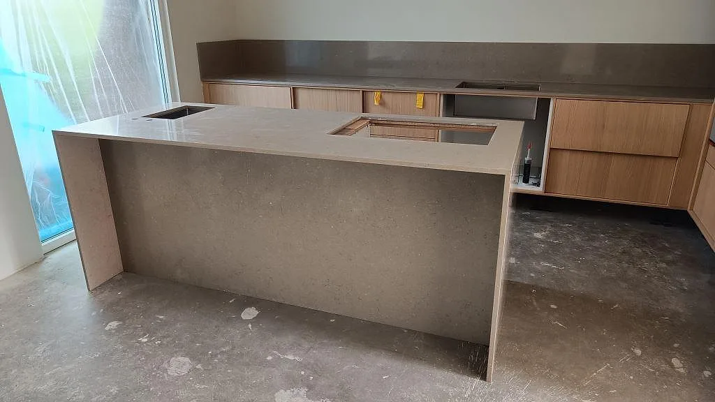 Polerad köksbänkskiva i Silestone Coral Clay, kvartskomposit, med köksödel, bakre bänkrad och uppvikt stänkskydd i ett kök i Lomma.