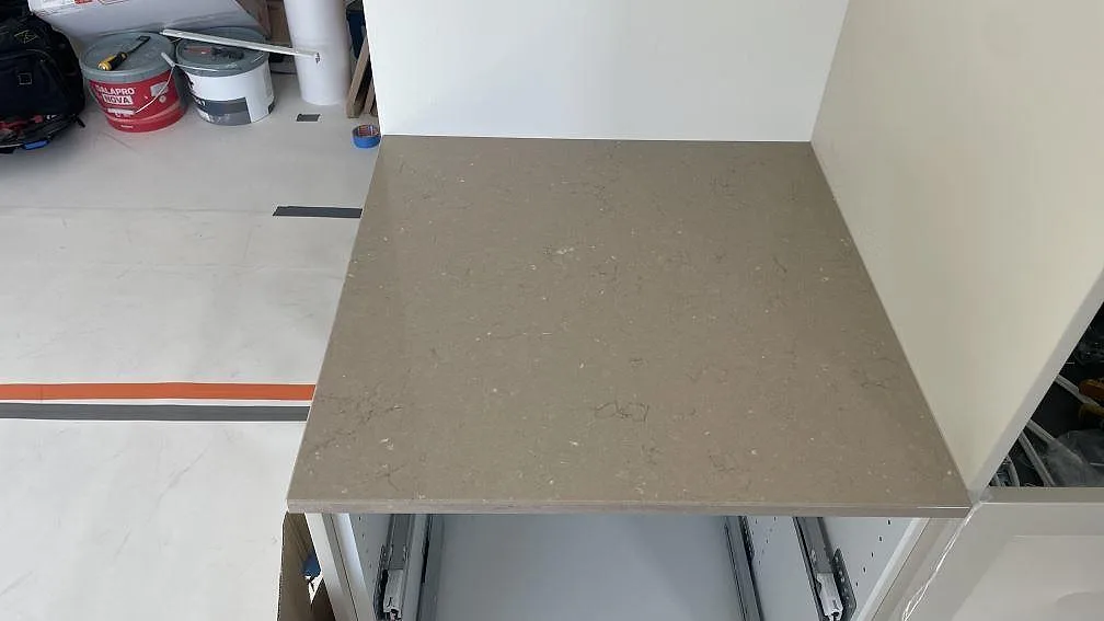 Närbild av polerad Silestone Coral Clay bänkskiva på öppna köksstommar med verktyg i bakgrunden under montering i Lomma.