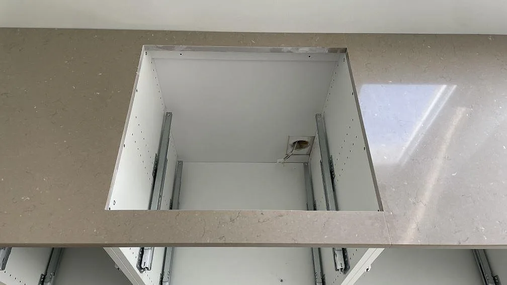 Förberett hälluttag i en polerad Silestone Coral Clay köksbänkskiva på öppna köksstommar under montering i Lomma.