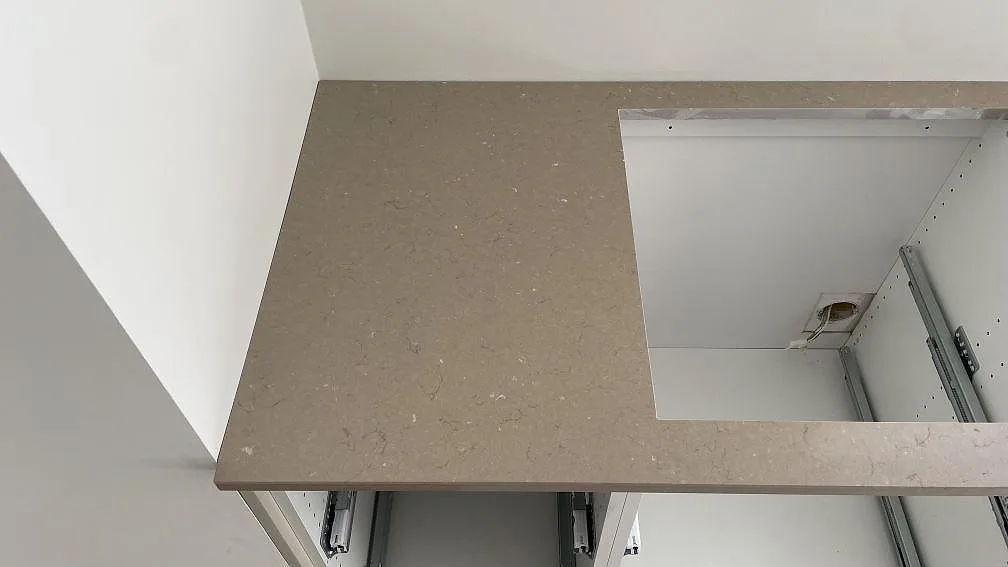 Sidovy av polerad Silestone Coral Clay köksbänkskiva med rektangulärt hälluttag och synlig greige kompositstruktur i Lomma.