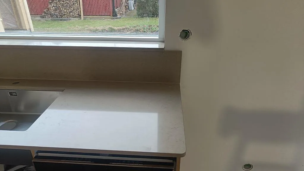 Köksbänkskiva i polerad Silestone Coral Clay med rostfri diskho, uppvikt stänkskydd och stort fönster i Lund.