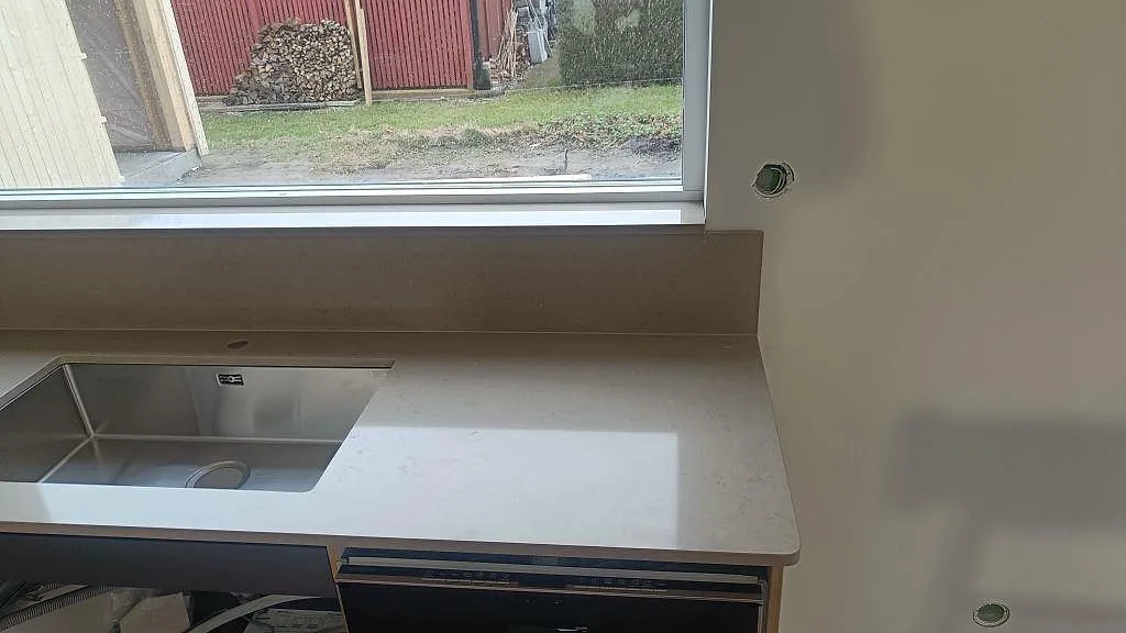Polerad Silestone Coral Clay vid underlimmad rostfri diskho, rundad bänkskivekant och matchande stänkskydd i Lund.