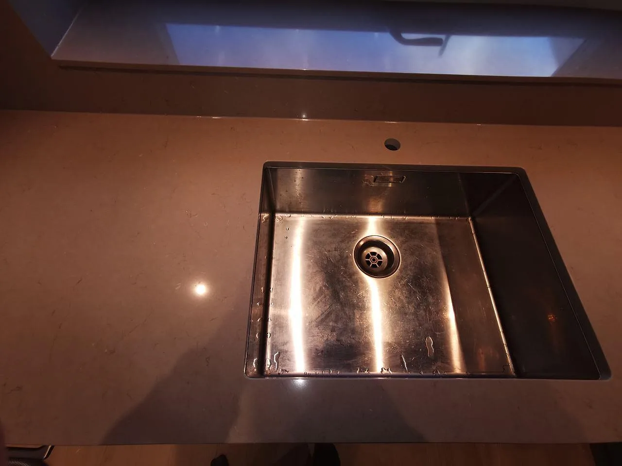 Underlimmad rostfri enkelho diskho i polerad Silestone Coral Clay bänkskiva i ett kök i Malmö.