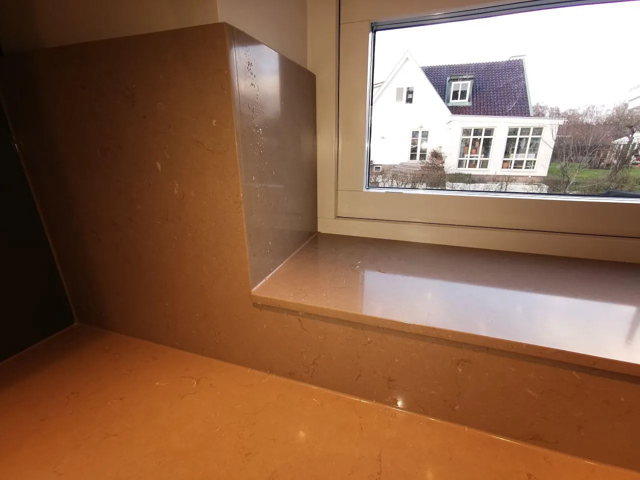 Fönsterbänk och uppvikt stänkkant i polerad Silestone Coral Clay med synlig ljus ådring i ett kök i Malmö.
