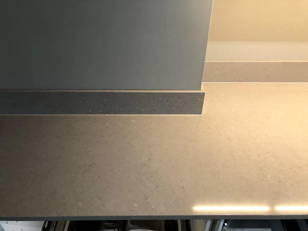 Hörndetalj av köksbänkskiva i Silestone Coral Clay som möter en grå köksö i matt greige kvartskomposit i ett kök i Malmö.
