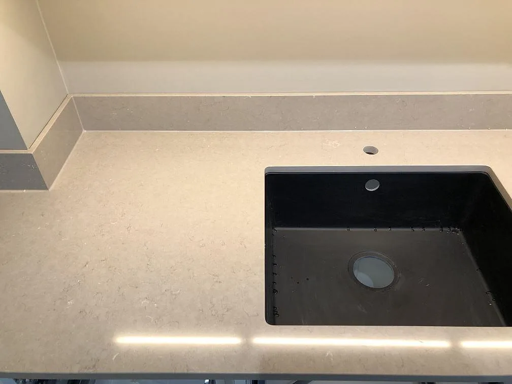 Svart underlimmad komposit-diskho med separat kranhål i en matt greige köksbänkskiva i Silestone Coral Clay i ett kök i Malmö.