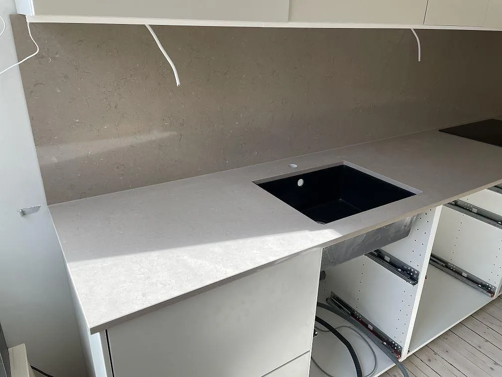 Detalj av underlimmad svart komposithoa i en Silestone Coral Clay bänkskiva, taupe kvartskomposit, i ett kök i Malmö.