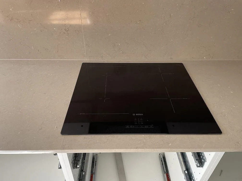 Köksbänkskiva i Silestone Coral Clay i Malmö med underlimmad svart fyrkantig komposithoa och separat blandarhål mot en blank stänkvägg.