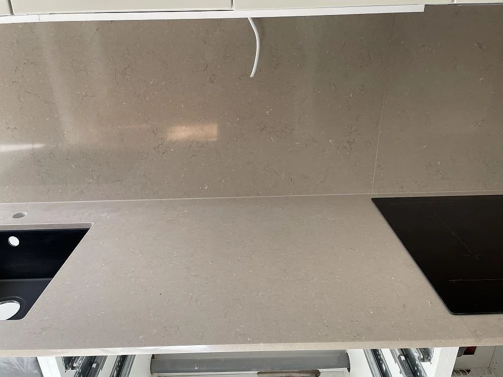 Svart Bosch induktionshäll infälld i en polerad Silestone Coral Clay bänkskiva med ljus ådring i ett kök i Malmö.