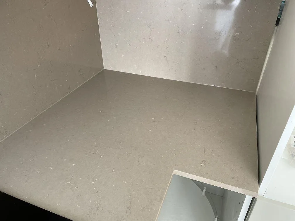Heltäckande stänkvägg i Silestone Coral Clay, taupe/greige kvartskomposit med gräddvit ådring, i ett innerhörn i ett kök i Malmö.