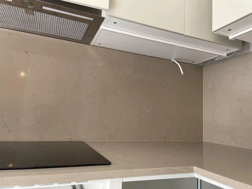 Innerhörn med dubbel stänkvägg i polerad Silestone Coral Clay, varm taupe kvartskomposit, i ett kök i Malmö.
