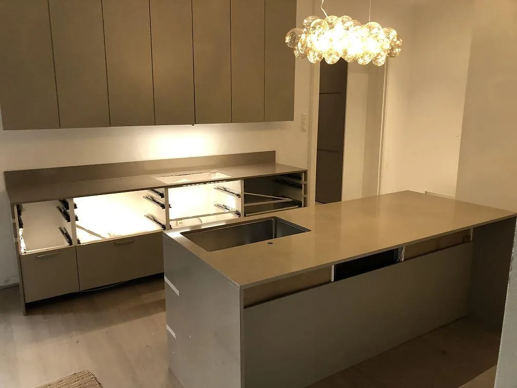 Köksö i Silestone Coral Clay med rostfri underlimmad diskho i topp och stenklädd gavel i ett kök i Malmö.