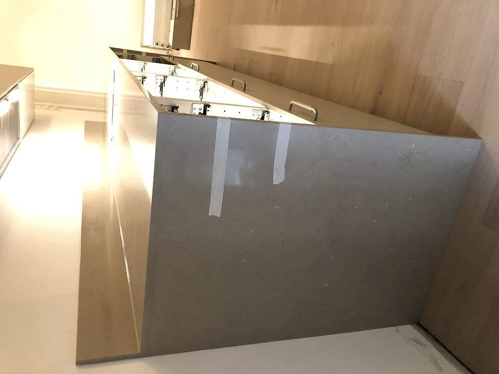 Köksbänkskiva och köksö i Silestone Coral Clay, polerad taupe kvartskomposit, med underlimmad rostfri diskho och tomt hällurtag i ett kök under montering i Malmö.