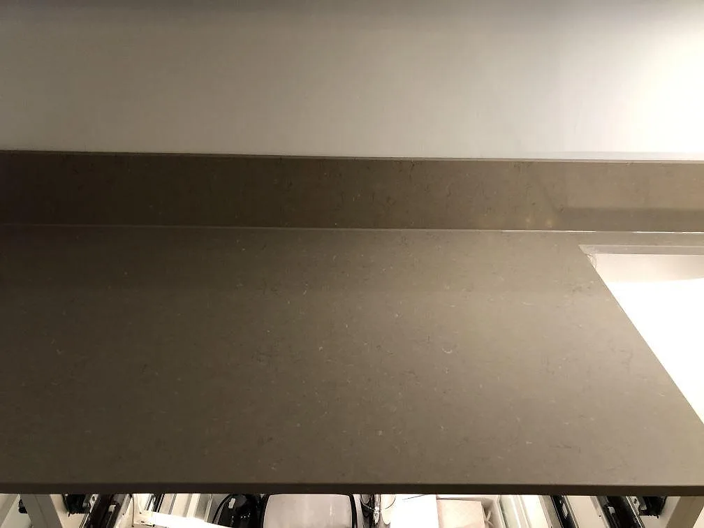 Bänkskiva i Silestone Coral Clay med låg uppvikt stänkkant och underlimmad diskho med vit inläggsskydd i ett kök i Malmö.