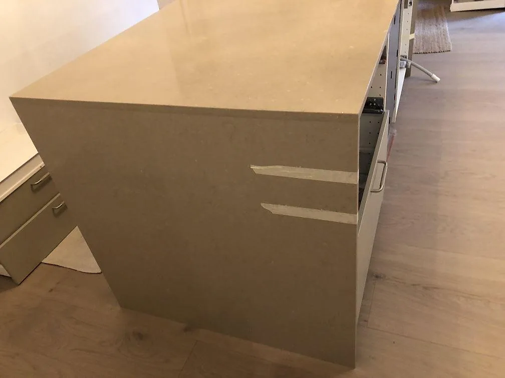 Köksö med waterfall-gavel i Silestone Coral Clay, tejpad under montering, mot ljust ekgolv i ett kök i Malmö.