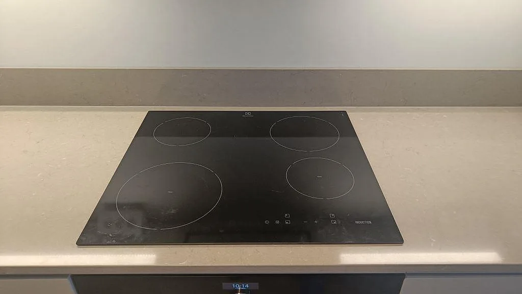 Hörn av Silestone Coral Clay bänkskiva i taupe med uppvikt stänkkant intill induktionshällen i ett kök i Malmö.