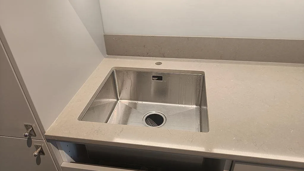 Bänkskiva i Silestone Coral Clay med underlimmad rostfri diskho till vänster och inbyggd induktionshäll till höger samt uppvikt stänkkant i samma sten, kök i Malmö.