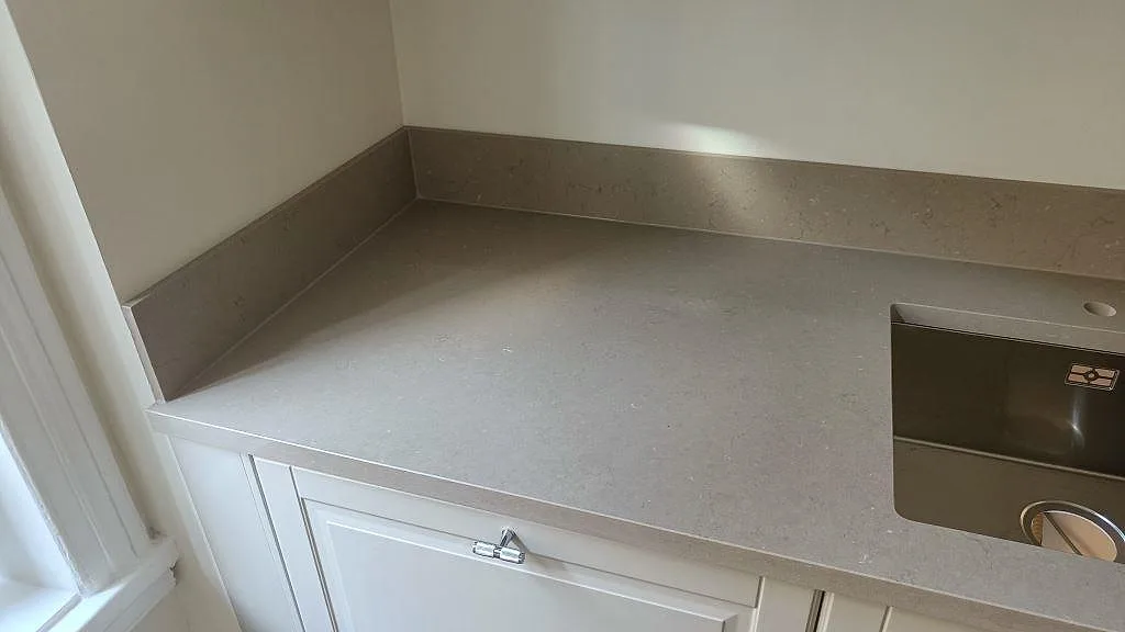 Hörn av Silestone Coral Clay bänkskiva med uppvikt stänkkant och rostfri diskho i ett kök i Malmö.