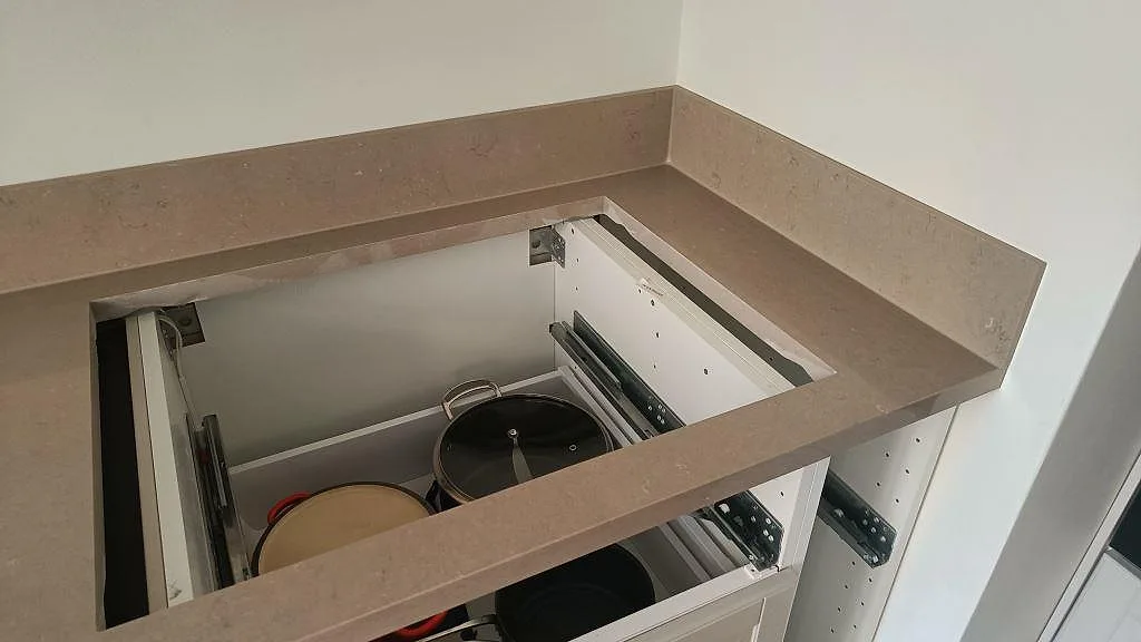 Hörn av Silestone Coral Clay bänkskiva med uppvikt stänkkant ovanför öppna köksstommar i Malmö.