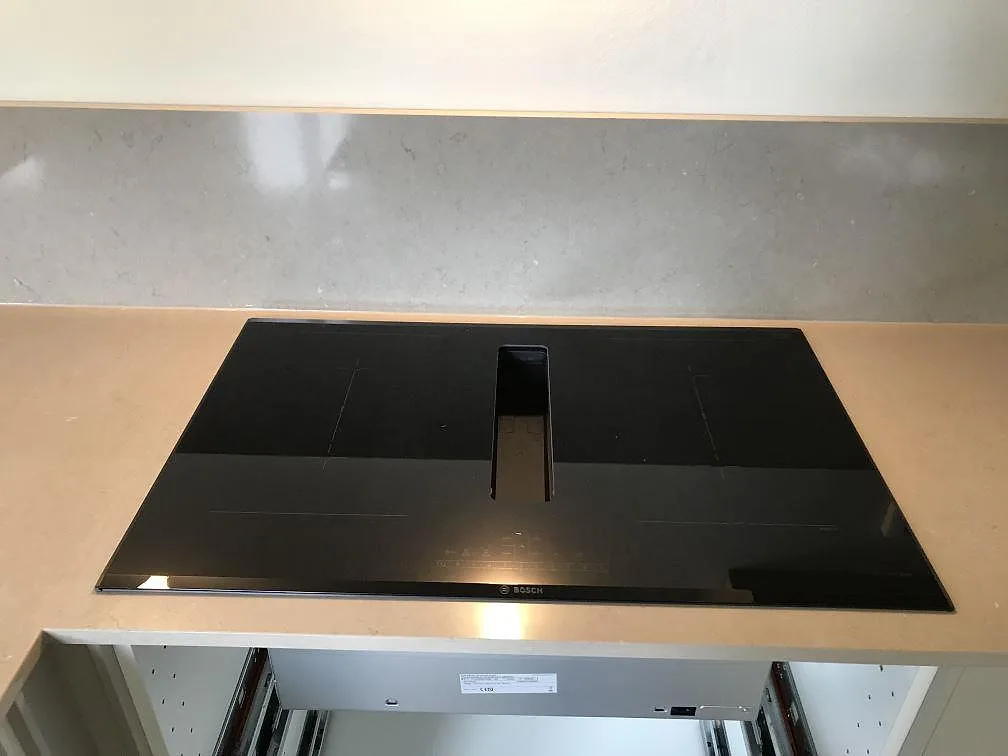 Bosch induktionshäll med integrerad fläkt infälld i en köksbänkskiva av Silestone Coral Clay i ett kök i Malmö.