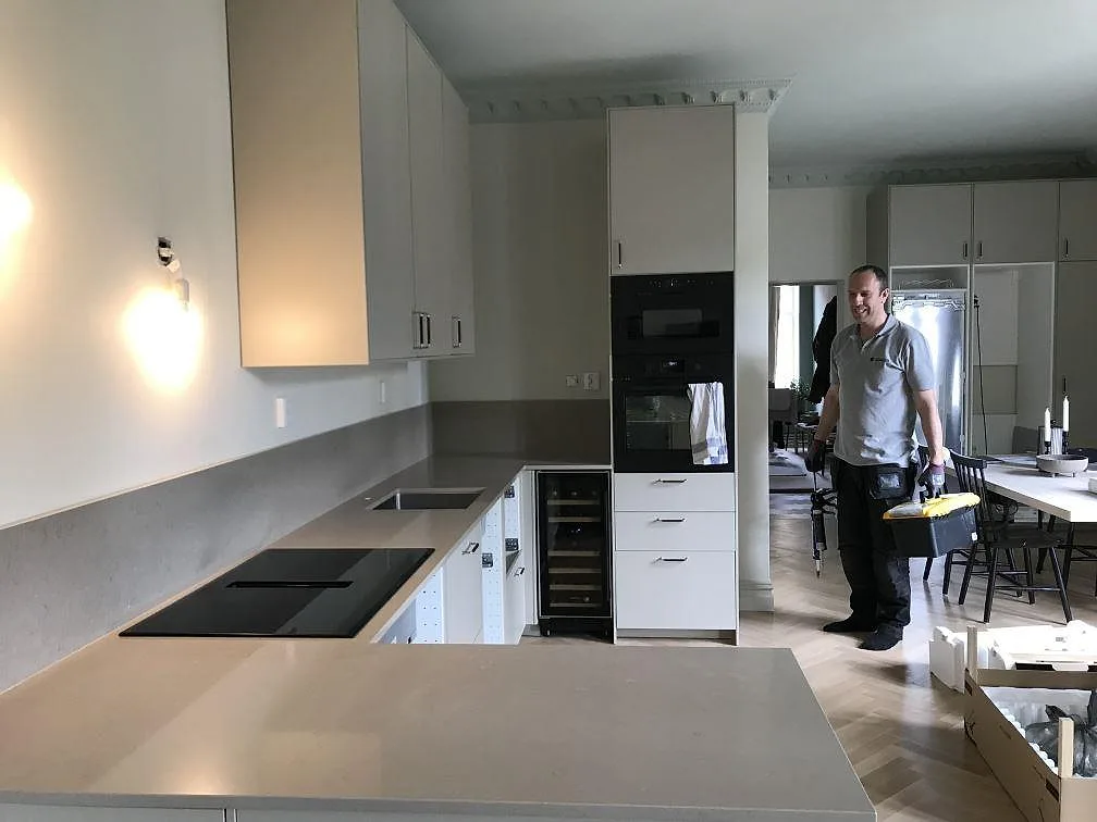 Installerad Silestone Coral Clay bänkskiva i matt kvartskomposit i ett kök i Malmö, med induktionshäll med integrerad fläkt och integrerad vinkyl.