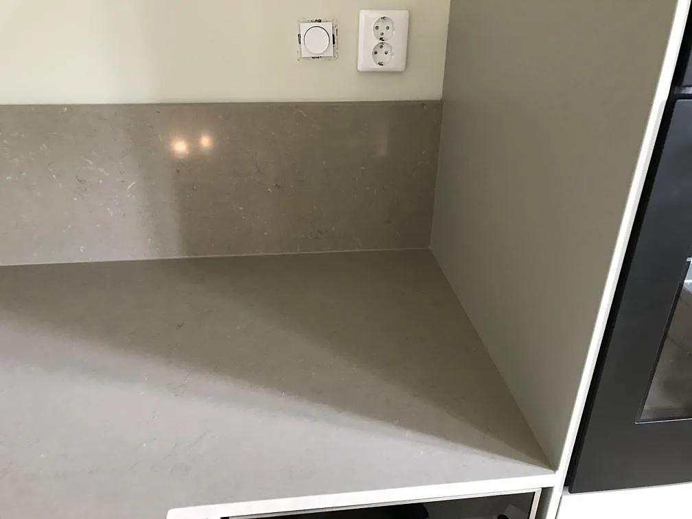 Detalj av köksbänkskiva i Silestone Coral Clay med uppvikt stänkkant och vägguttag i ett kök i Malmö.