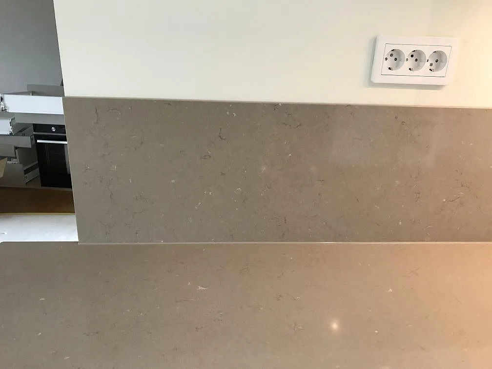 Bänkrad i Silestone Coral Clay med underlimmad rostfri diskho och infälld induktionshäll, med stänkvägg i samma sten, i ett kök i Malmö.