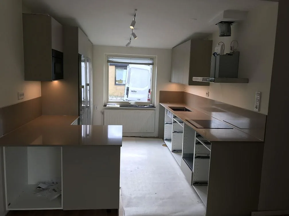 Infälld induktionshäll i en köksbänkskiva i Silestone Coral Clay med heltäckande stänkvägg i samma taupe kvartskomposit i Malmö.