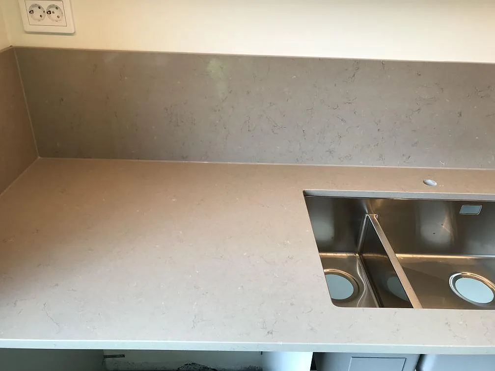 Köksbänkskiva i Silestone Coral Clay, varm taupe kvartskomposit, i ett galleri-format kök under montering med köksö, induktionshäll och fönster i Malmö.