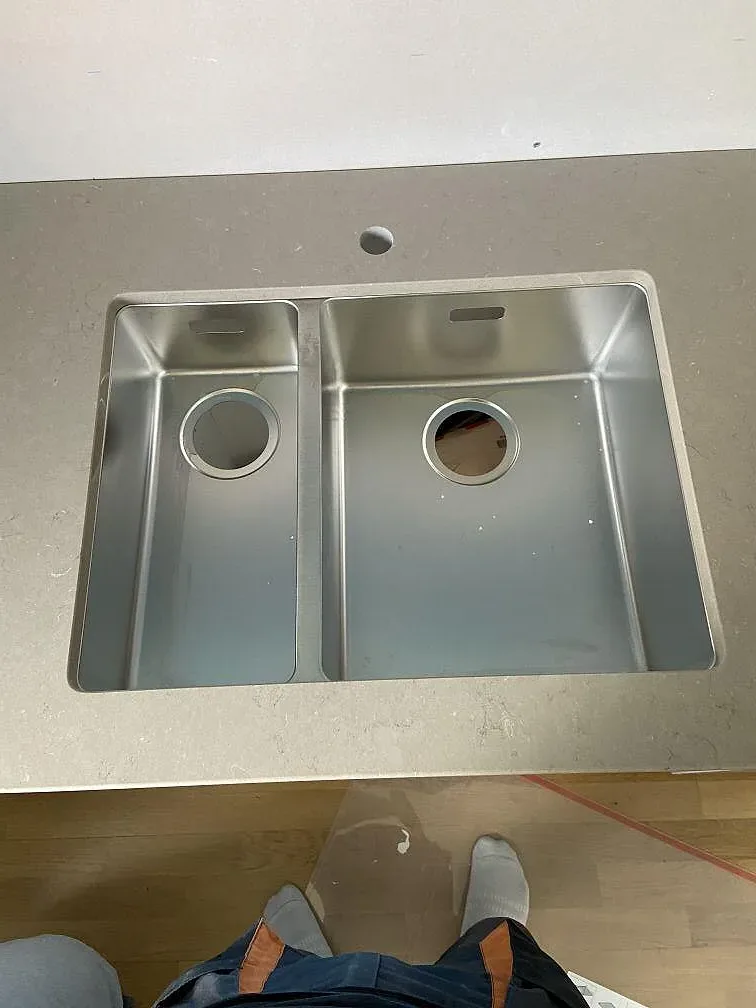 Underlimmad rostfri diskho med 1,5 hoar i polerad Silestone Coral Clay-bänkskiva i ett kök i Malmö.