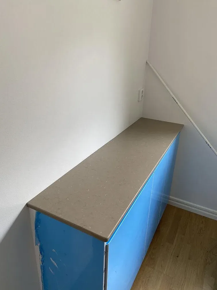 Hörn av monterad köksbänkskiva i gråbeige Silestone Coral Clay mot vit köksstomme i ett kök i Malmö.