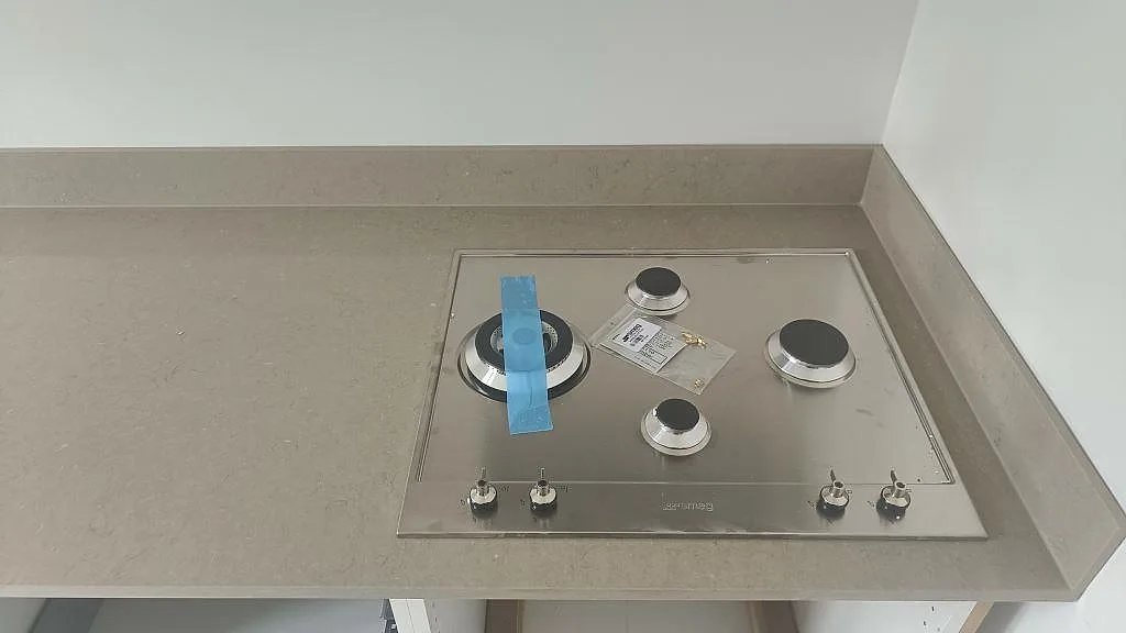 Infälld rostfri gashäll med fyra brännare i polerad Silestone Coral Clay köksbänkskiva i Malmö.