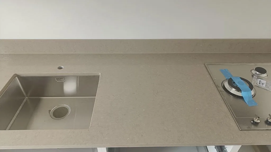 Köksbänkskiva i Silestone Coral Clay sedd ovanifrån med underlimmad rostfri diskho, blandarhål och infälld gashäll i ett kök i Malmö.