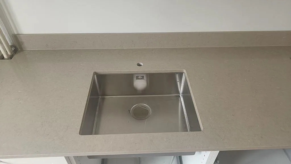 Underlimmad rostfri diskho i polerad Silestone Coral Clay med separat blandarhål, köksbänkskiva i greige kvartskomposit i Malmö.