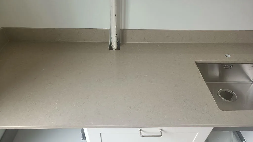 Polerad Silestone Coral Clay bänkskiva med uppvikt stänkkant och underlimmad rostfri diskho i ett kök i Malmö.