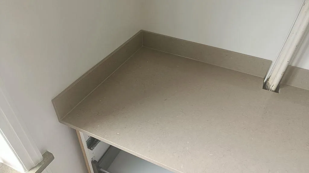 Köksbänkskiva i greige Silestone Coral Clay med uppvikt kant mot vägg, polerad kvartskomposit i Malmö.