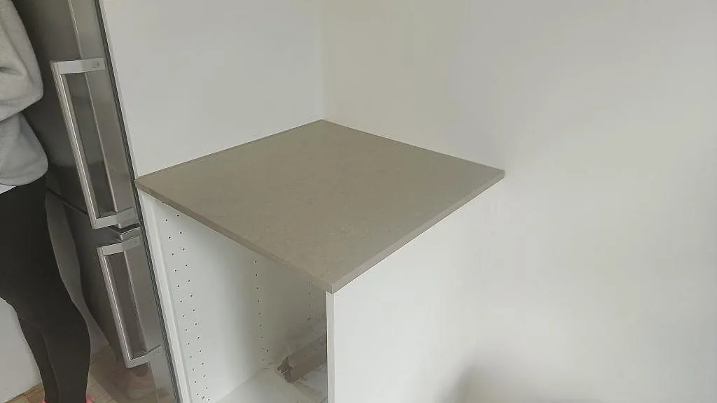 Bänkskiva i Silestone Coral Clay, polerad greige kvartskomposit, monterad intill kylskåpet i ett kök i Malmö.