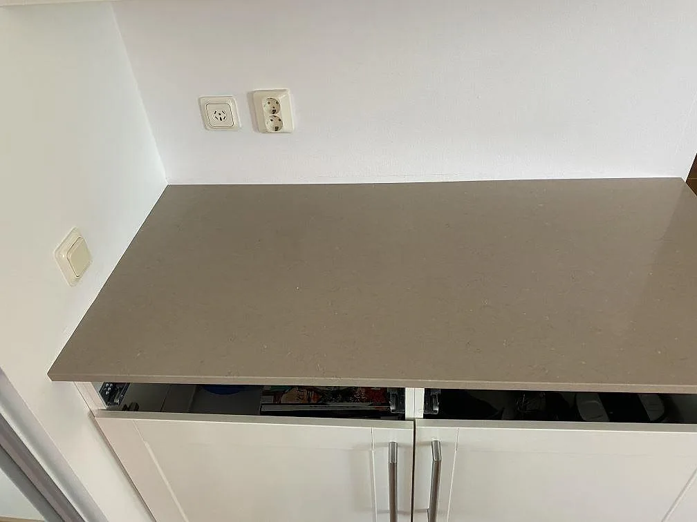 Bänkskiva i beige Silestone Coral Clay med polerad yta över vita köksluckor i ett kök i Malmö.