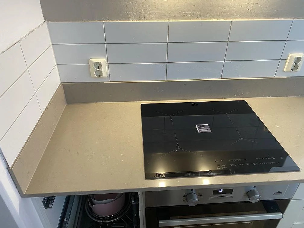 Köksbänkskiva i Silestone Coral Clay med infälld induktionshäll och vitt kakel som stänkskydd i ett kök i Malmö.