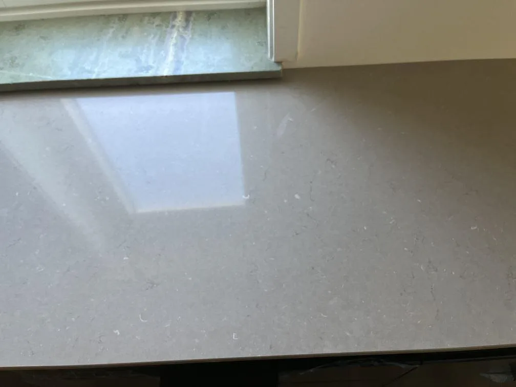 Närbild på polerad Silestone Coral Clay bänkskiva vid ett fönster som visar den varma taupefärgade ytan med diskret ådring i Malmö.