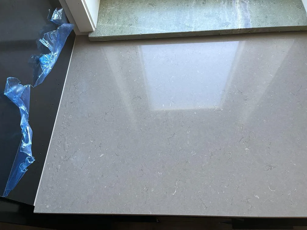 Ovanifrån på polerad Silestone Coral Clay köksbänkskiva med mjuk grå ådring i ett kök i Malmö.