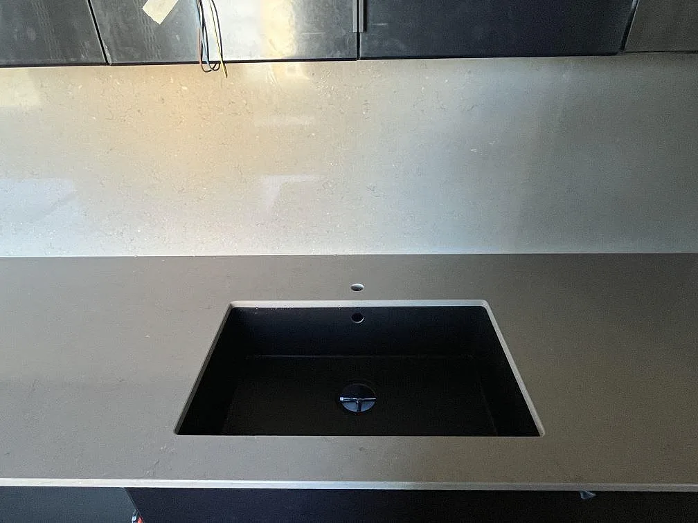 Underlimmad svart kompositdiskho i polerad Silestone Coral Clay köksbänkskiva med borrat blandarhål i Malmö.