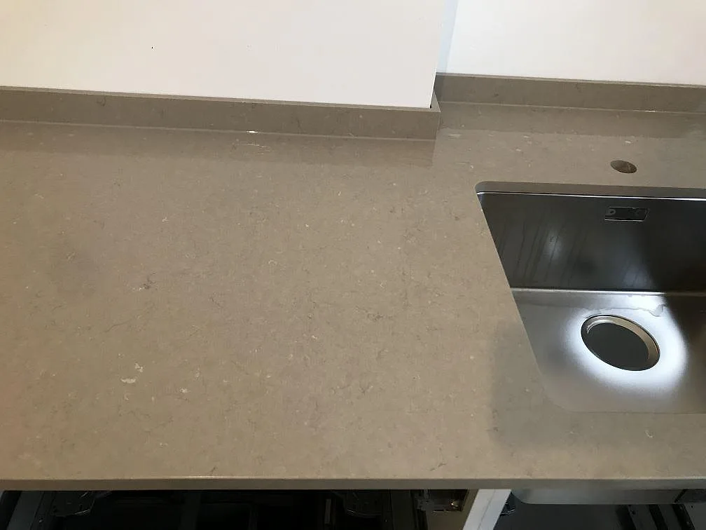 Köksbänkskiva i Silestone Coral Clay, varm gråbeige polerad kvartskomposit, med underlimmad rostfri diskho i ett kök i Malmö.