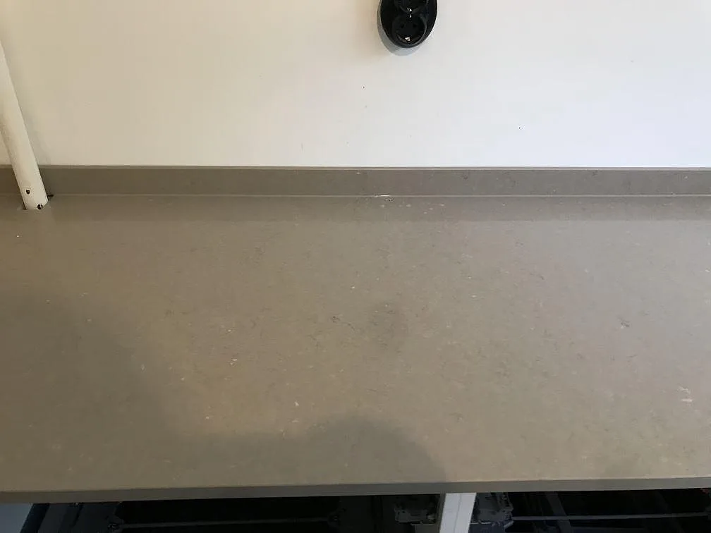 Bänkskiva i Silestone Coral Clay längs vägg med uppvikt stänkkant i ett kök i Malmö, polerad kvartskomposit.