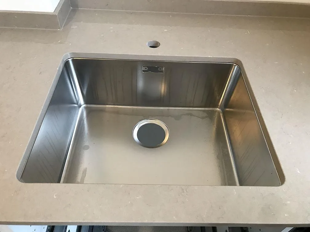 Underlimmad rostfri diskho ovanifrån i bänkskiva av Silestone Coral Clay i ett kök i Malmö, polerad kvartskomposit.